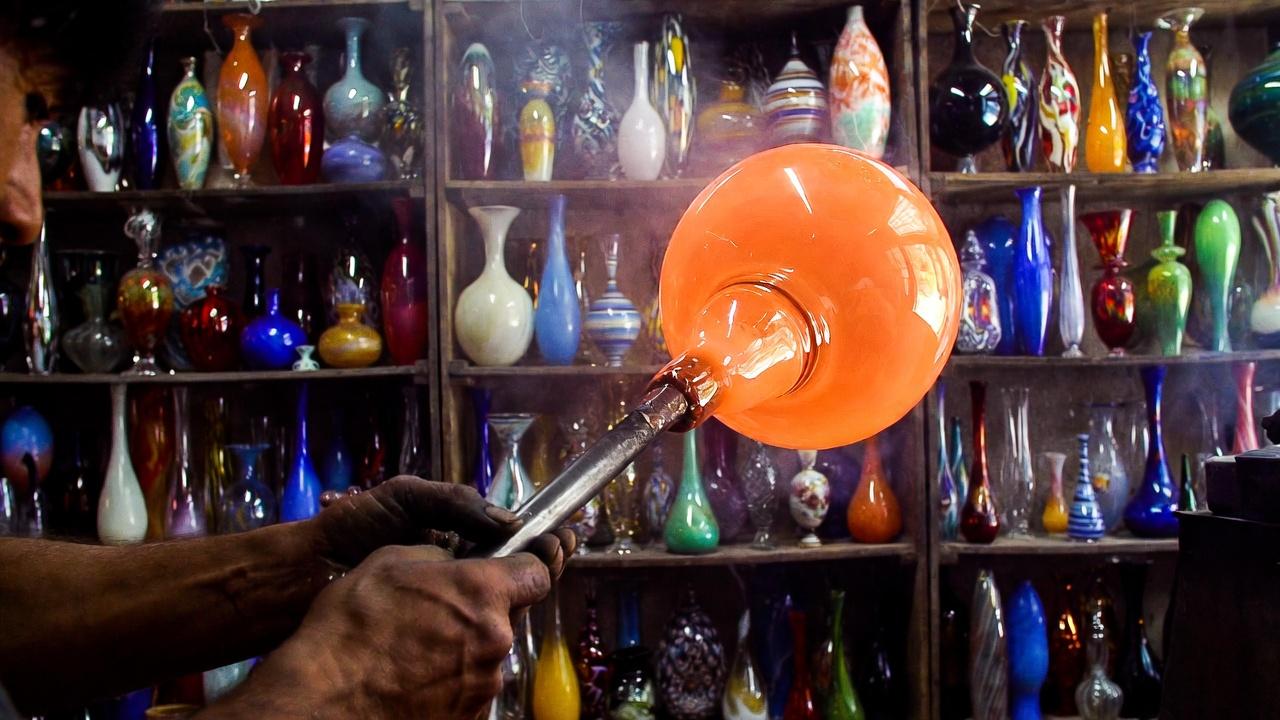 Glass-blowing artisan shaping colorful blown glass in Tlaquepaque workshop